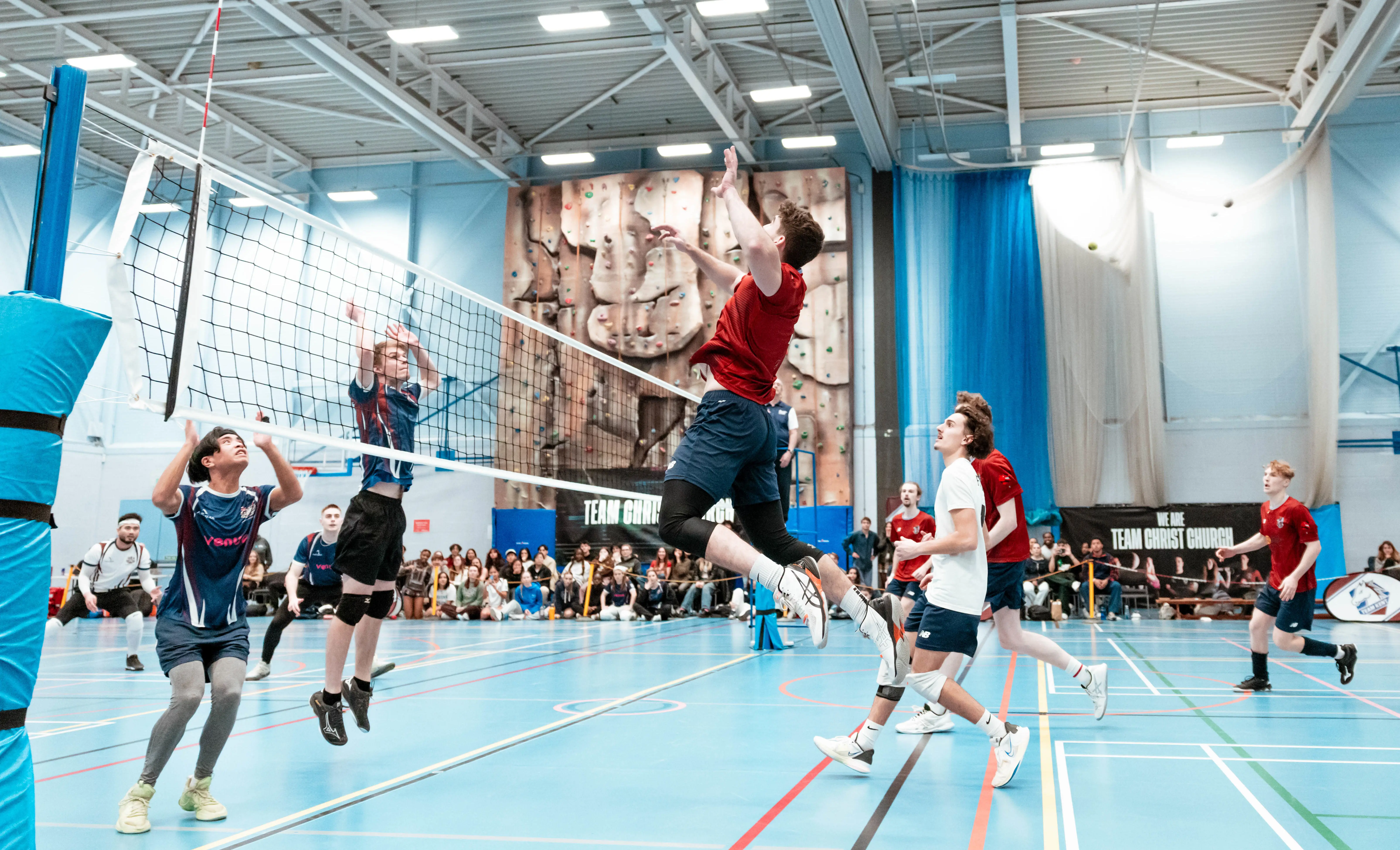 Two teams playing volleyball in the sports hall