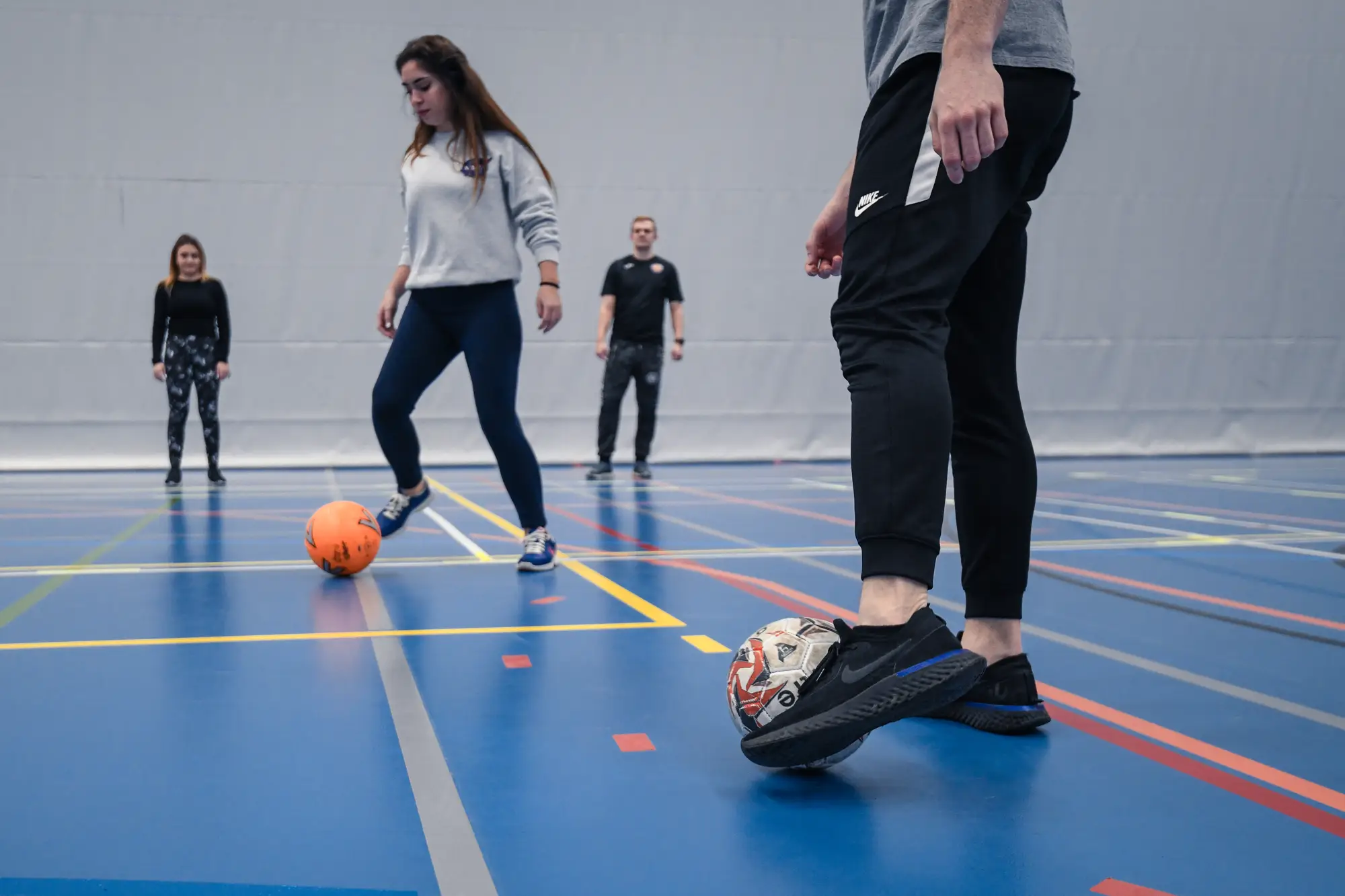 students dribbling football in the sports hall