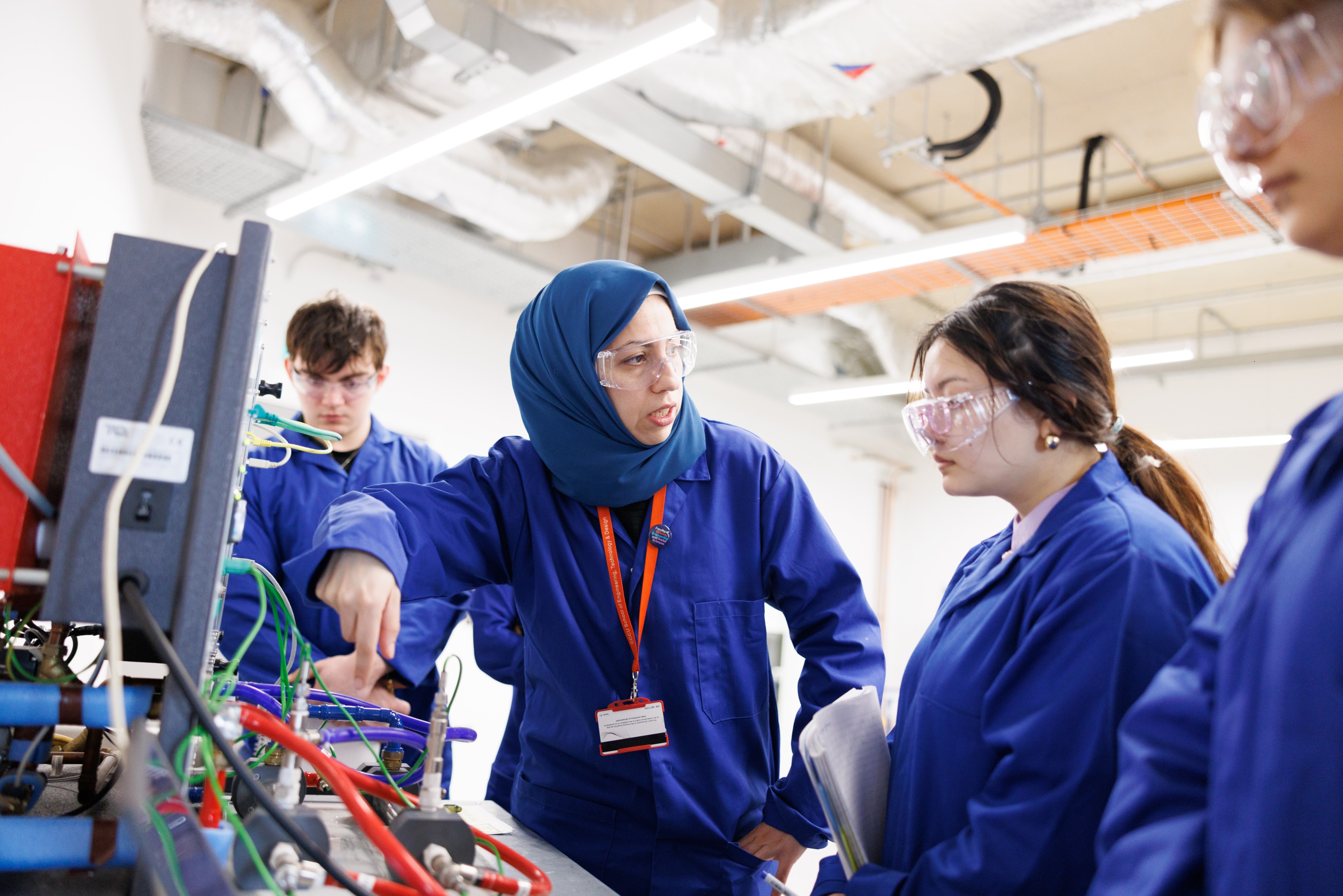 female engineering lecturer and student working in the lab wearing blue lab coats 