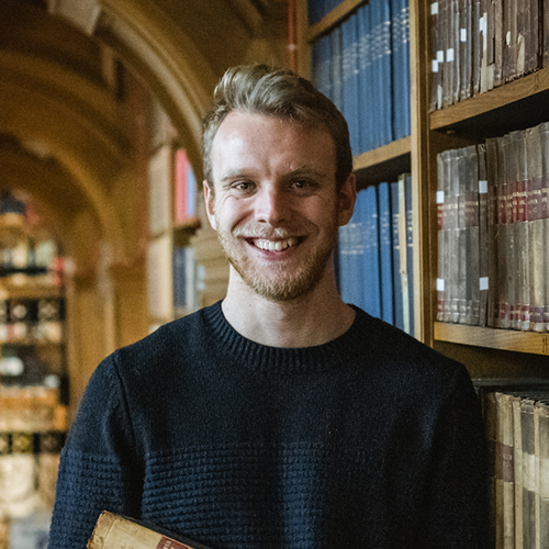 A student in an archive smiling at the camera.
