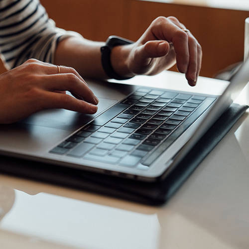 Hands typing on a laptop keyboard