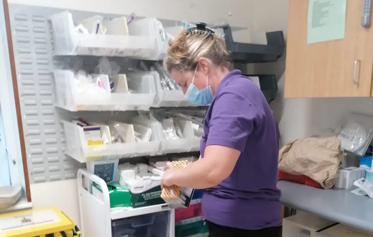 Emily working in a hospital, collecting supplies from a store area