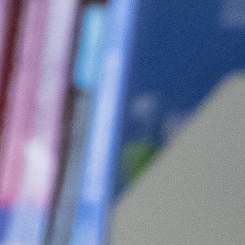 A blonde woman is working at a computer in the library. Shelves of books can be seen behind her.