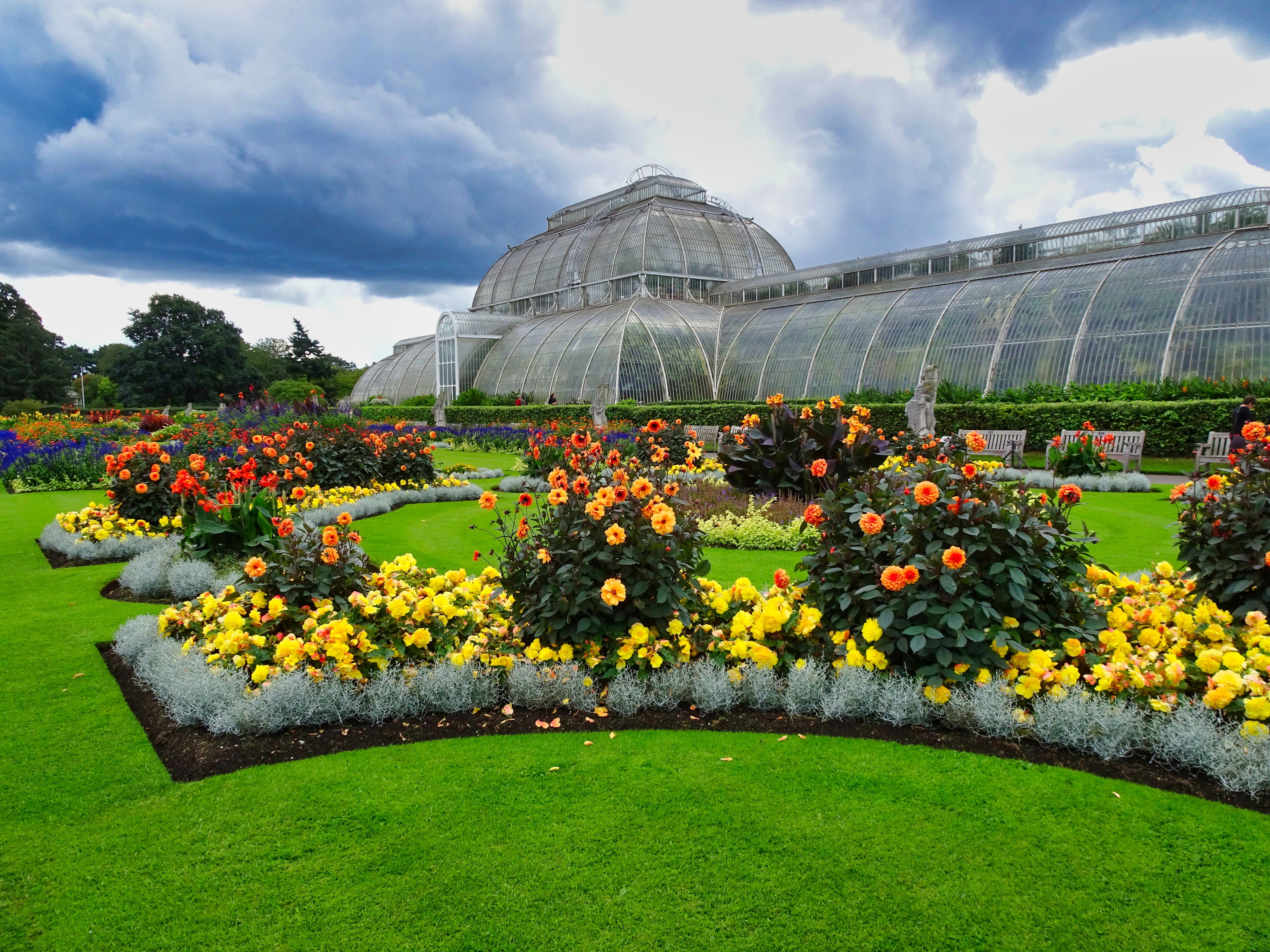 The gardens with blooming flowers outside of the large glasshouse at Kew Gardens. 