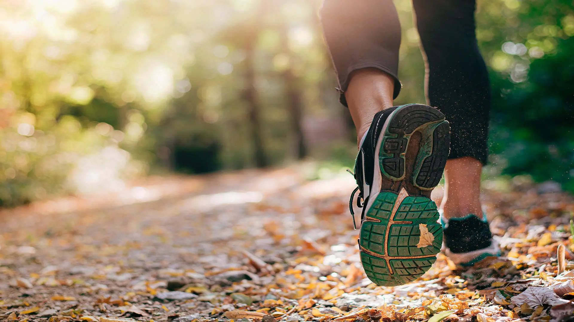 A persons legs walking on a trail