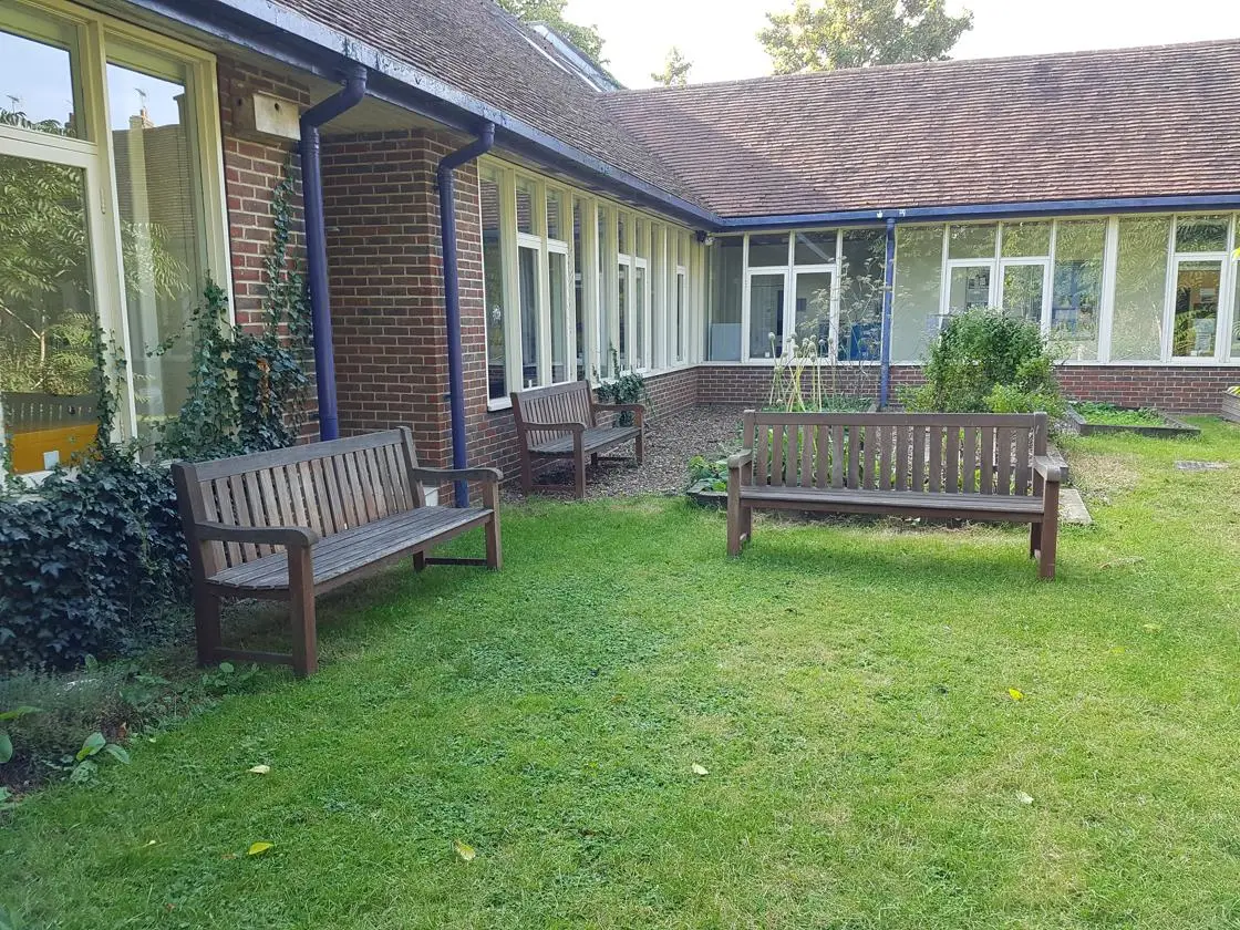 Image of wooden benches located on the grass outside the Johnson Building on Canterbury campus