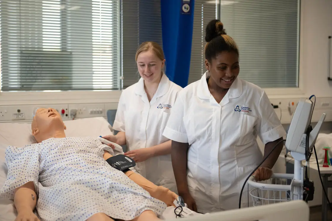 Two female students practicing their nursing skills on a mannequin. 