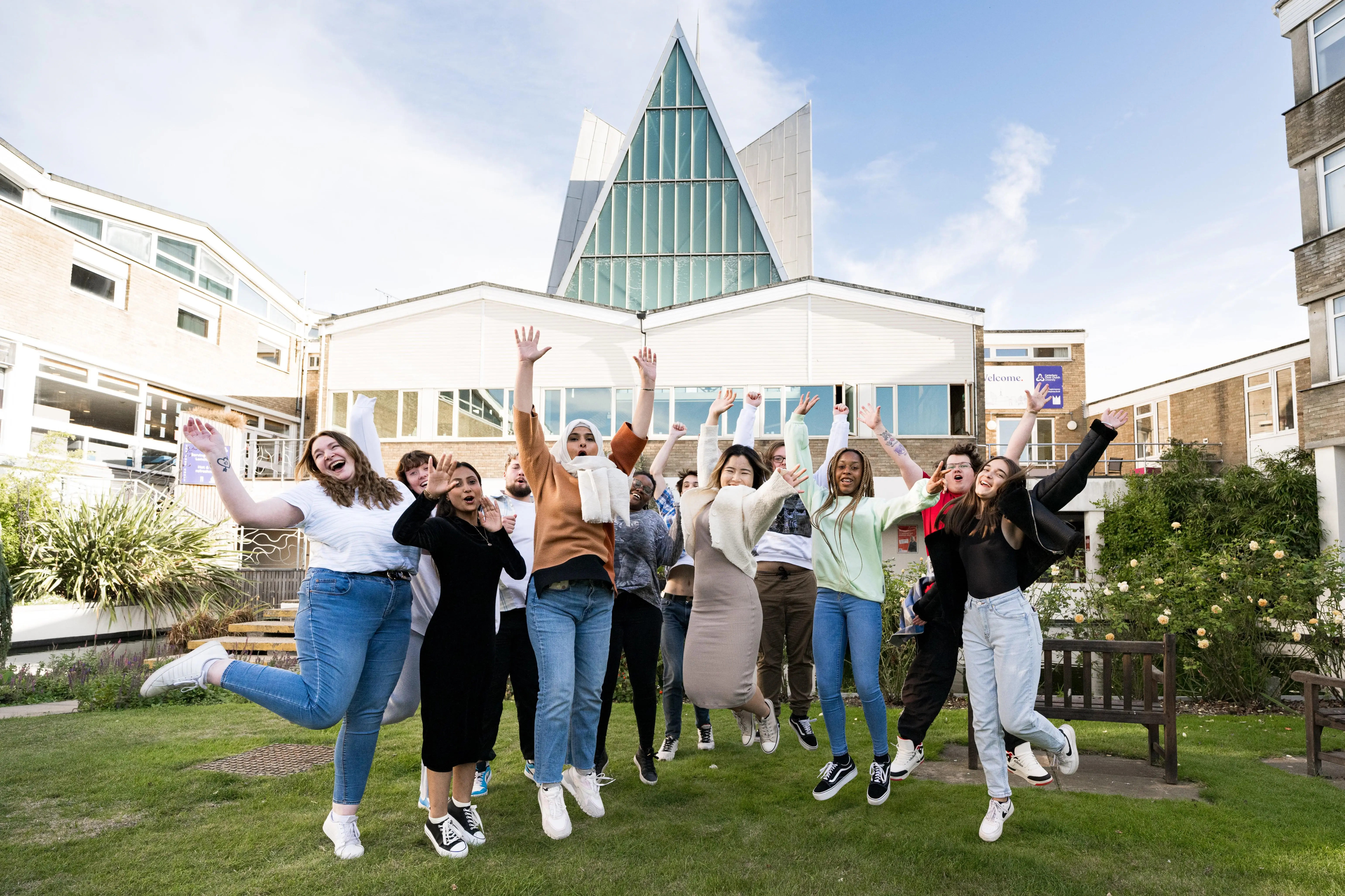 Group of student ambassadors jumping outside, with The Chapel in the background