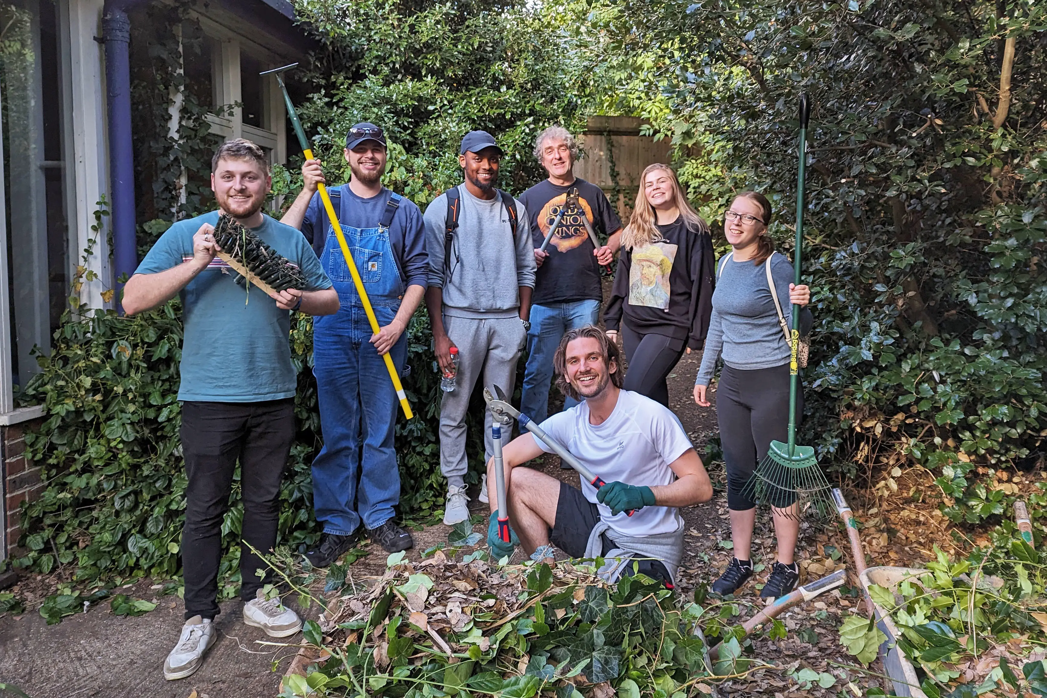 Staff and students holding gardening tools in the Johnson Wellbeing Garden