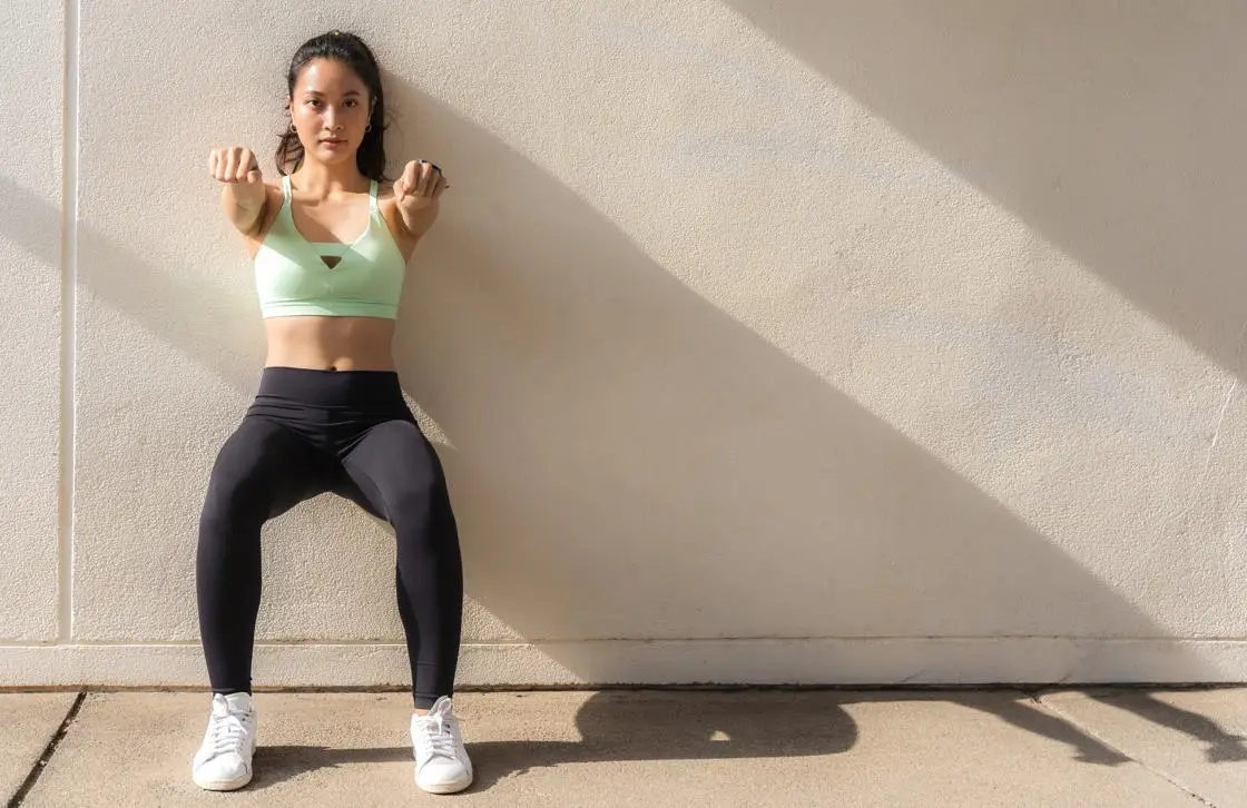 Young woman conducting a wall sit exercise